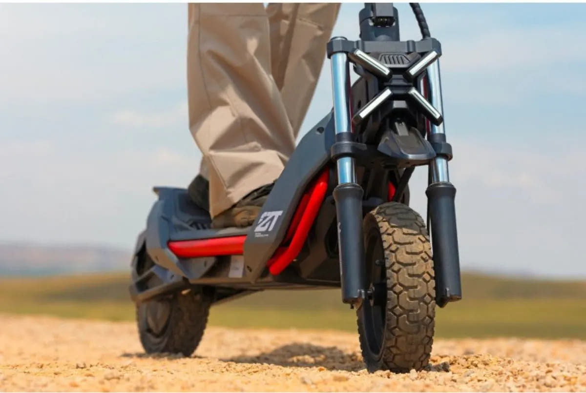 Vue basse de la Segway Ninebot ZT3 Pro sur du gravier, fourche télescopique et pneus crantés